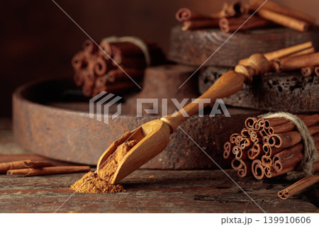 Wooden spoon with cinnamon powder and cinnamon sticks. 139910606