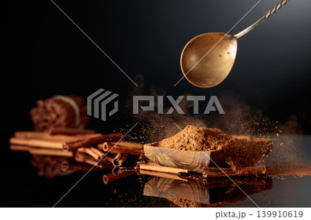 Cinnamon powder is poured into a wooden dish. 139910619