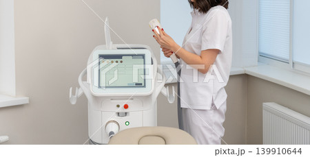 Female cosmetologist operating modern laser beauty equipment Female cosmetologist operating modern laser beauty equipment 139910644