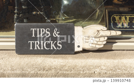 Tips and tricks words symbol. Concept words Tips and tricks on beautiful black wooden sign. Beautiful shopfront background. Business tips and tricks motivational support concept. Copy space. 139910748