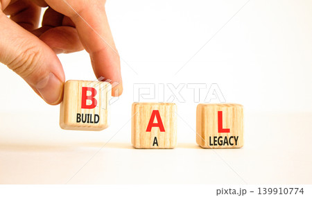 BAL build a legacy symbol. Concept words BAL build a legacy on beautiful wooden blocks. Beautiful white background. Businessman hand. Business BAL build a legacy concept. Copy space 139910774
