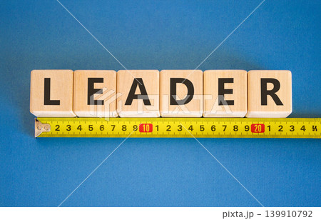 Leadership and leader symbol. Concept word Leader on beautiful wooden blocks. Beautiful blue background. Beautiful yellow tape measure ruler. Business leader and leadership concept. Copy space. 139910792