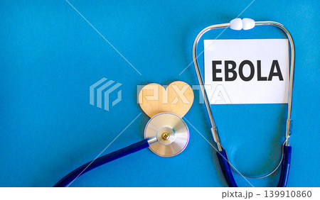 Ebola virus medical words symbol. Concept word Ebola on beautiful white paper. Beautiful blue background. Beautiful wooden heart. Stethoscope. Medical Ebola virus concept. Copy space. 139910860