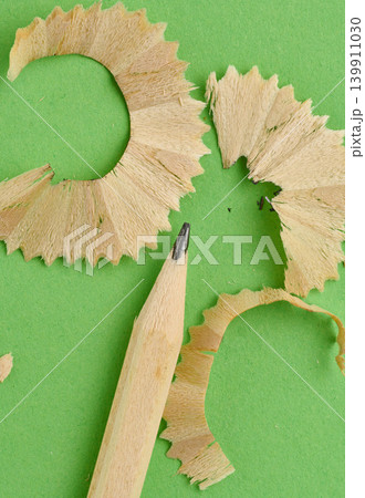 Close-up of a sharpened pencil surrounded by swirls of wood shavings on a green paper background Close-up of a sharpened pencil surrounded by swirls of wood shavings on a green paper background 139911030