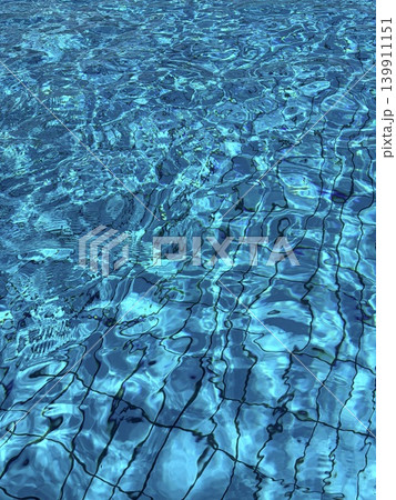A radical image of clear, transparent blue water in a tiled swimming pool. Water ripples and sun glare in the pool. A radical image of clear, transparent blue water in a tiled swimming pool. Water ripples and sun glare in the pool. 139911151
