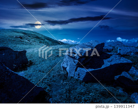 Carpathian mountain summer landscape at night. full moon over meadow with huge stones among the grass on top of the hillside near the peak of mountain range. mysterious alpine meadow and rolling hills 139911347