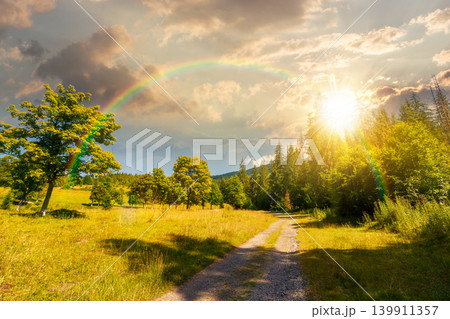 sunset over view of a country road in carpathian mountains for travel. road journey through forested countryside summer scenery. forest on the background hill. sky with clouds and rainbow 139911357