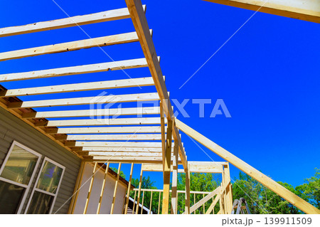 Workers are building roof trusses frame for house with wooden beams 139911509