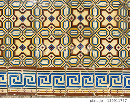 Intricate traditional Portuguese azulejo tiles feature geometric patterns in blue, yellow, and brown, showcasing classic decorative ceramic craftsmanship. 139911737