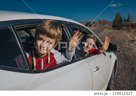 Happy mother and son waving hands from car window Happy mother and son waving hands from car window 139912927
