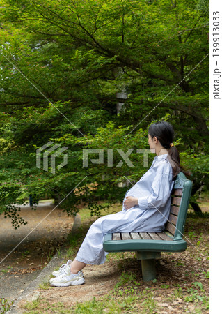 公園のベンチに座って休憩しているお腹の大きい妊婦 公園のベンチに座って休憩しているお腹の大きい妊婦 139913033