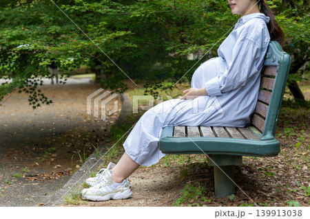 公園のベンチに座って休憩しているお腹の大きい妊婦 公園のベンチに座って休憩しているお腹の大きい妊婦 139913038