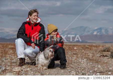 Mother, son and shih tzu dog looking away on winter mountains background 139913204