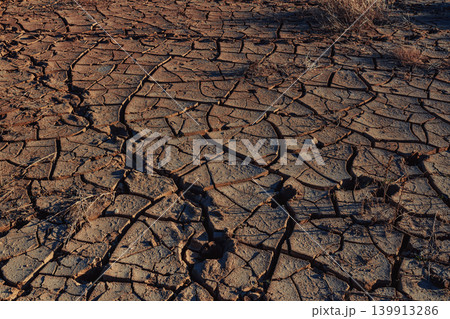 Cracked ground in desert at sunset Cracked ground in desert at sunset 139913286