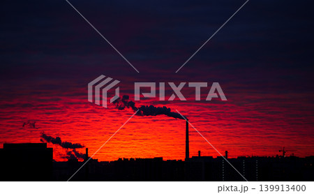 Evening cityscape with smoky chimneys against a red sunset Evening cityscape with smoky chimneys against a red sunset 139913400