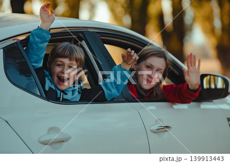 Happy mother and son waving hands from car window Happy mother and son waving hands from car window 139913443