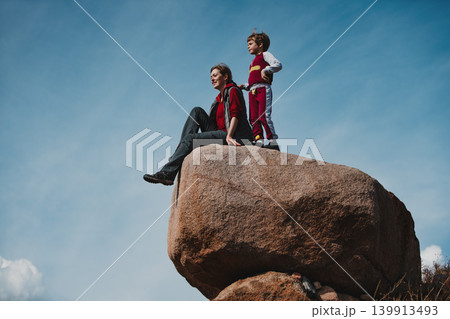 Mother and son sits on a big boulder and admiring the scenery Mother and son sits on a big boulder and admiring the scenery 139913493