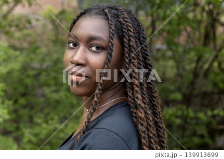 Young African woman portrait in lush green nature, outdoor lifestyle Young African woman portrait in lush green nature, outdoor lifestyle 139913699