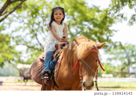 happy toddler girl riding the brown horse happy toddler girl riding the brown horse 139914145