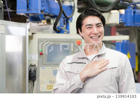 工場の製造現場で笑顔を見せる指差しのオススメポーズの若手技術者の品質管理と設備点検イメージカメラ目線 工場の製造現場で笑顔を見せる指差しのオススメポーズの若手技術者の品質管理と設備点検イメージカメラ目線 139914183