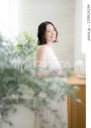 笑顔でお腹に手を添える日本人女性の妊婦さん、マタニティライフスタイルイメージの笑顔 笑顔でお腹に手を添える日本人女性の妊婦さん、マタニティライフスタイルイメージの笑顔 139914194