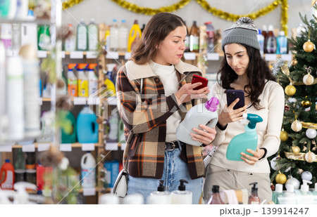 Female friends client scanning QR code on package laundry fabric softener and tile cleaner Female friends client scanning QR code on package laundry fabric softener and tile cleaner 139914247