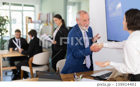 Elderly bank manager shaking hands with adult female client Elderly bank manager shaking hands with adult female client 139914401