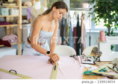 Woman dressmaker making markings on textiles 139914654