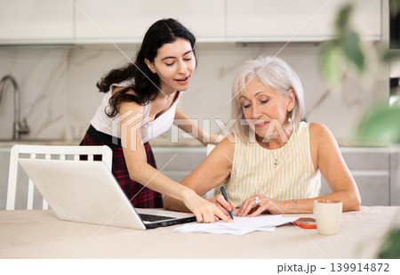 Elderly woman discussing deal with saleswoman in kitchen Elderly woman discussing deal with saleswoman in kitchen 139914872