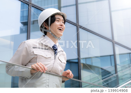 都会のビル背景でヘルメットを被る笑顔を見せる若手男性作業員と建設キャリアイメージ 就活やキャリア 都会のビル背景でヘルメットを被る笑顔を見せる若手男性作業員と建設キャリアイメージ 就活やキャリア 139914908