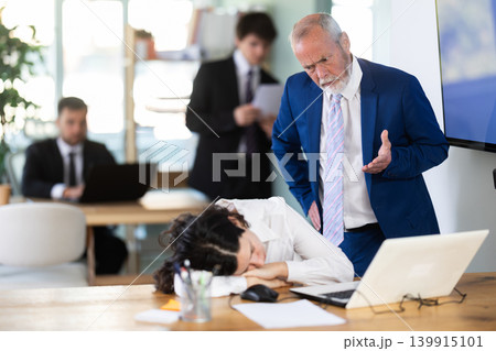Strict mature man boss scolding girl office worker for improper operation on laptop in office Strict mature man boss scolding girl office worker for improper operation on laptop in office 139915101