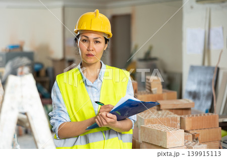 Woman making notes on indoor construction site Woman making notes on indoor construction site 139915113