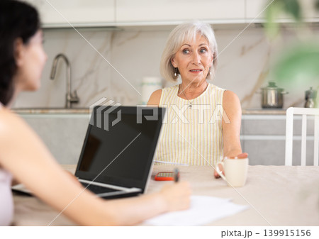 Elderly woman discussing deal with saleswoman in kitchen 139915156
