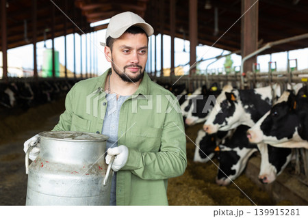Focused man farmer carrying big milk can 139915281