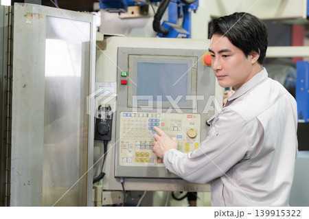 工場や製造現場で設備を操作する若手作業員と生産管理イメージ　パネルをタップする 139915322
