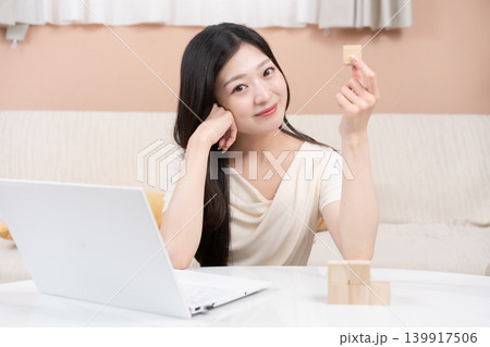 積立投資や資産形成をイメージする若い女性 ノートパソコンと積み木 積立投資や資産形成をイメージする若い女性 ノートパソコンと積み木 139917506