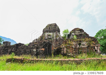 Ancient ruined red brick towers of Hindu temple complex surrounded by green grass at My Son Sanctuary site in Vietnam Ancient ruined red brick towers of Hindu temple complex surrounded by green grass at My Son Sanctuary site in Vietnam 139917609