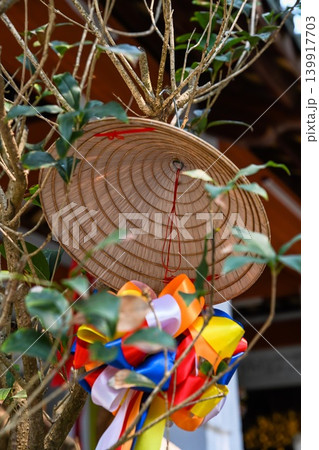 Close up of a traditional vietnamese conical hat non la hanging with vibrant colorful ribbons on a tree branch outdoor Close up of a traditional vietnamese conical hat non la hanging with vibrant colorful ribbons on a tree branch outdoor 139917703