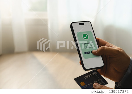 Hand holding smartphone with completed mobile payment transaction and credit card during online banking process for digital finance, banking, transfer, and secure payment management. Hand holding smartphone with completed mobile payment transaction and credit card during online banking process for digital finance, banking, transfer, and secure payment management. 139917872