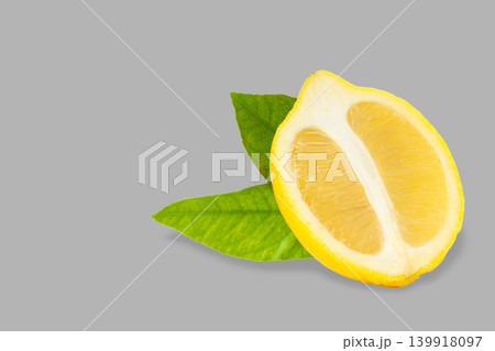 Lemon half with green leaves on a gray surface in bright light Lemon half with green leaves on a gray surface in bright light 139918097