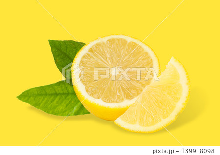 Fresh lemon slice with green leaves on bright yellow Fresh lemon slice with green leaves on bright yellow 139918098