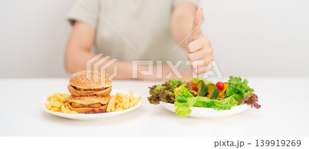 happy woman choose vegetables Salad and thumbs up gesture. Healthy and Unhealthy Food Choice, Calories and Nutrition of vegetables and Hamburger. dieting, weight loss control, junk food and lifestyle happy woman choose vegetables Salad and thumbs up gesture. Healthy and Unhealthy Food Choice, Calories and Nutrition of vegetables and Hamburger. dieting, weight loss control, junk food and lifestyle 139919269