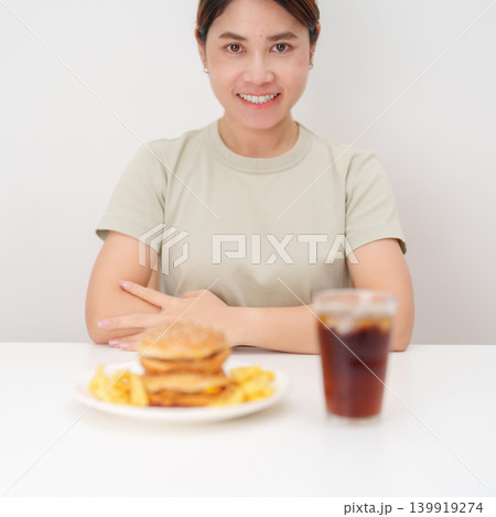 happy woman with Juicy beef burger with melted cheddar cheese, potato chips and carbonated Soft drinks. Unhealthy, High calorie, Fast food craving, Obesity, diet, weight loss, junk food and lifestyle happy woman with Juicy beef burger with melted cheddar cheese, potato chips and carbonated Soft drinks. Unhealthy, High calorie, Fast food craving, Obesity, diet, weight loss, junk food and lifestyle 139919274