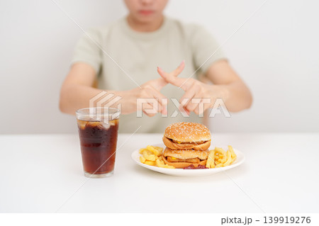Unhappy woman showing Rejecting and refusing with Juicy beef burger, potato chips and carbonated Soft drinks. Unhealthy, High calorie, Fast food craving, Obesity, diet, weight loss and junk food Unhappy woman showing Rejecting and refusing with Juicy beef burger, potato chips and carbonated Soft drinks. Unhealthy, High calorie, Fast food craving, Obesity, diet, weight loss and junk food 139919276