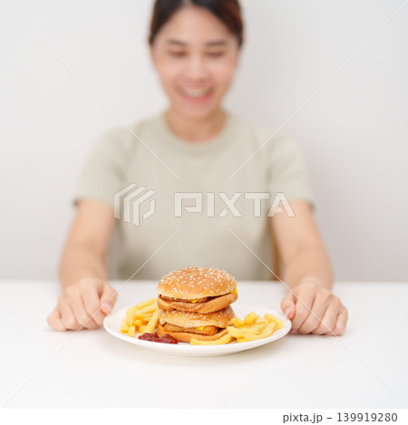 happy woman eating Juicy beef burger with melted cheddar cheese, potato chips. Unhealthy, High calorie, Fast food craving, Obesity, diet, weight loss, junk food and lifestyle happy woman eating Juicy beef burger with melted cheddar cheese, potato chips. Unhealthy, High calorie, Fast food craving, Obesity, diet, weight loss, junk food and lifestyle 139919280