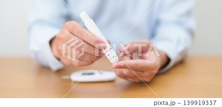 Hand using lancet pen on finger with Blood drop glucose testing or Diabetes checking by digital blood glucose meter. blood sugar level, Diabetes Day, Glycemia, Hypoglycemia, Hyperglycemia and insulin Hand using lancet pen on finger with Blood drop glucose testing or Diabetes checking by digital blood glucose meter. blood sugar level, Diabetes Day, Glycemia, Hypoglycemia, Hyperglycemia and insulin 139919337