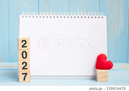 blank notebook and 2027 cubes with red heart shape decoration on blue wooden table background. New Year NewYou, Goal, Resolution, health, Love and Happy Valentine day concept blank notebook and 2027 cubes with red heart shape decoration on blue wooden table background. New Year NewYou, Goal, Resolution, health, Love and Happy Valentine day concept 139919478