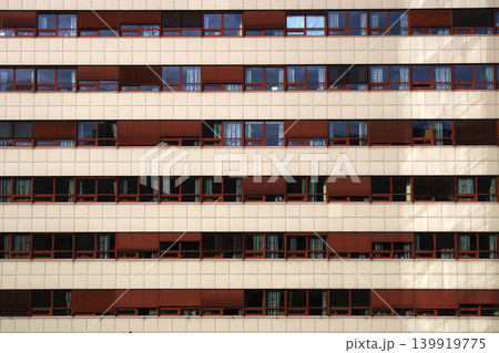 Building facade displaying rows of windows and red blinds 139919775