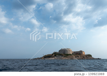 An ancient fortress is perched on a small island surrounded by the calm sea An ancient fortress is perched on a small island surrounded by the calm sea 139921069