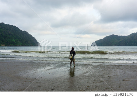 Local fisherman casting a fishing rod from the shoreline on a tropical beach in Malang, Indonesia. 139921170